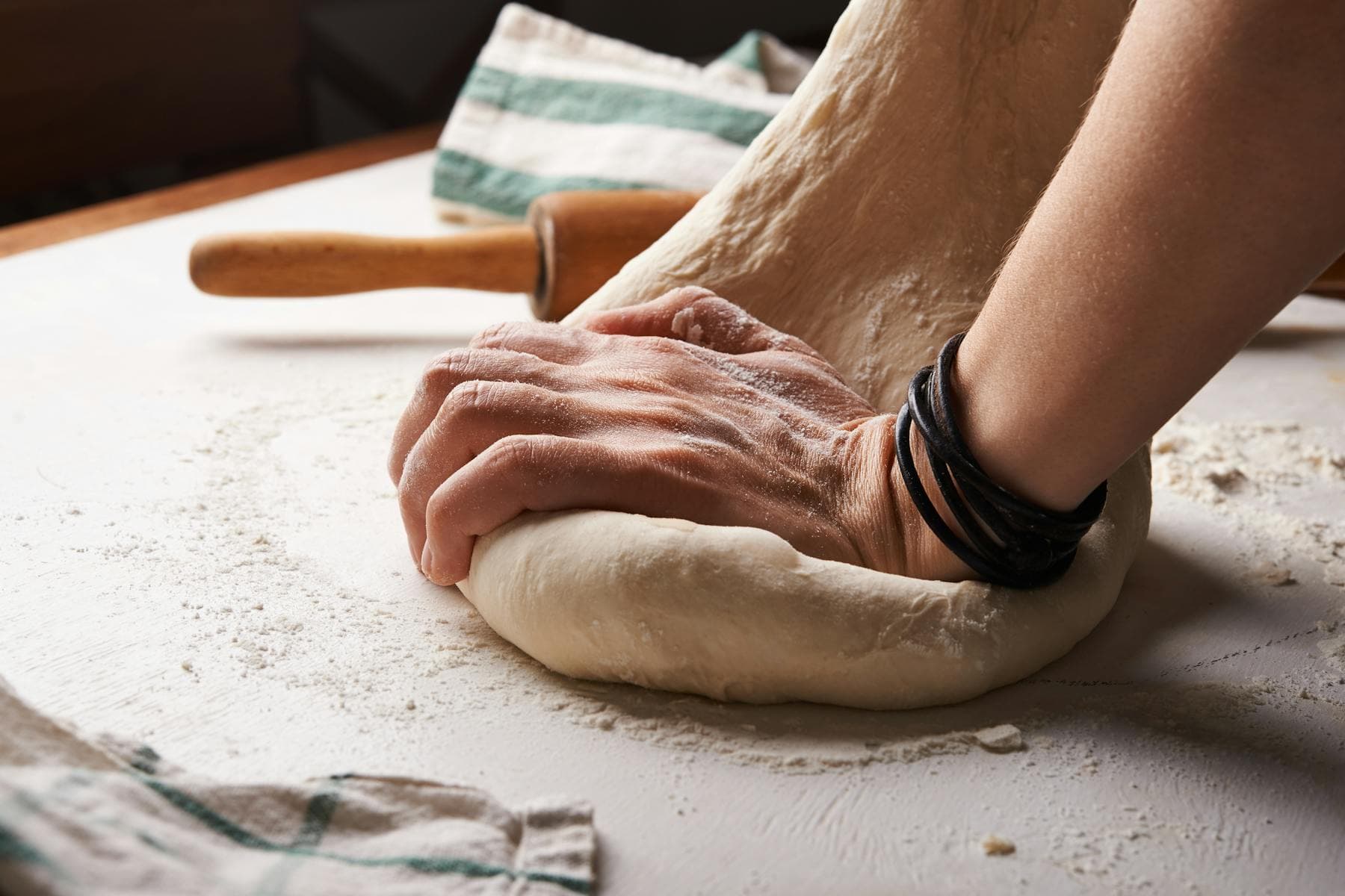 Hands preparing food at a kitchen counter, natural light